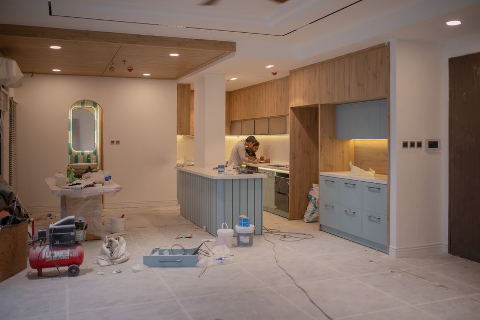 An indoor construction site during a building renovation, featuring three white plastic containers with lids placed on the floor, surrounded by scaffolding and construction materials. The surfaces of 